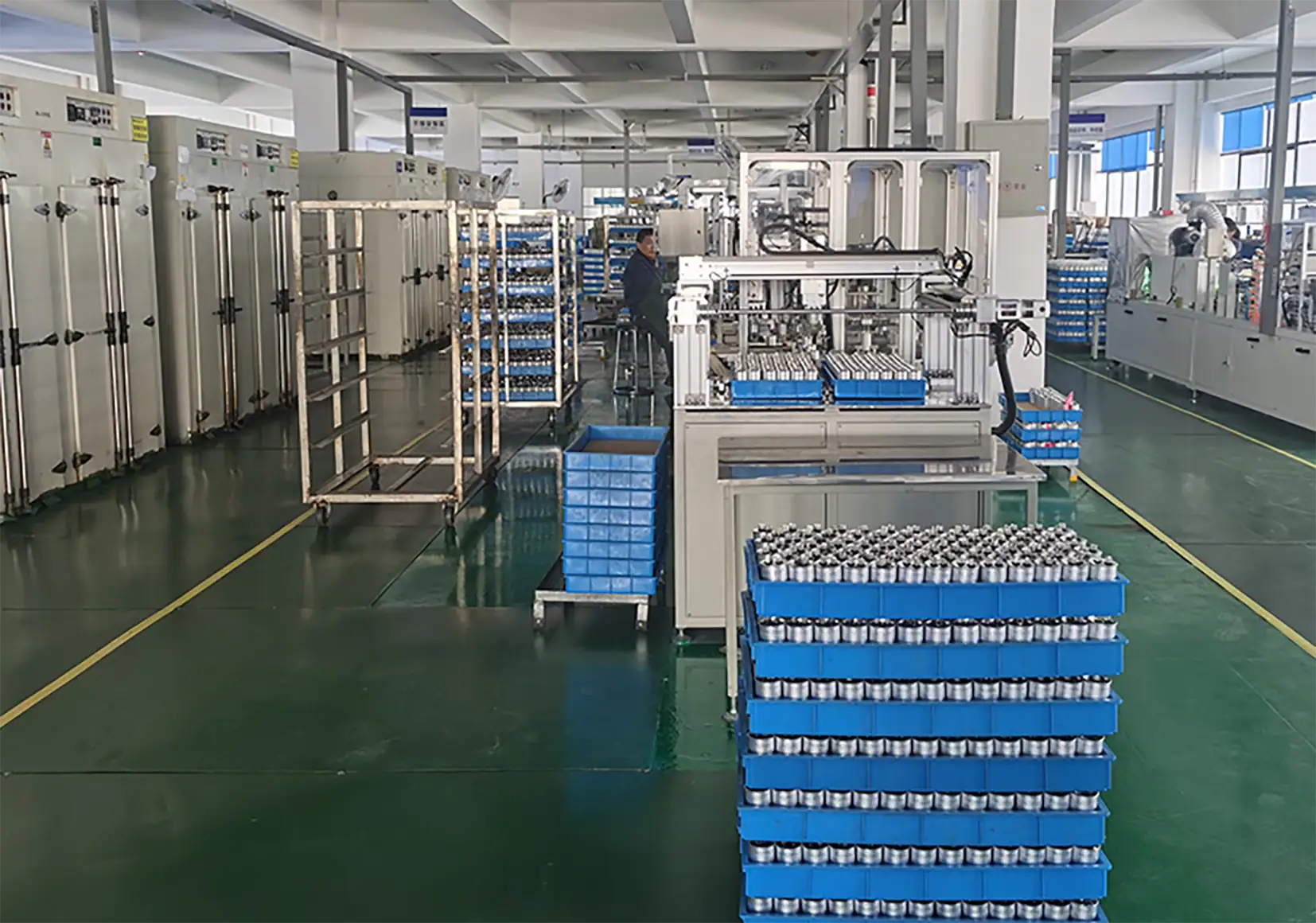 Automated industrial machinery for packaging products in a factory setting, with conveyor belts and blue containers.